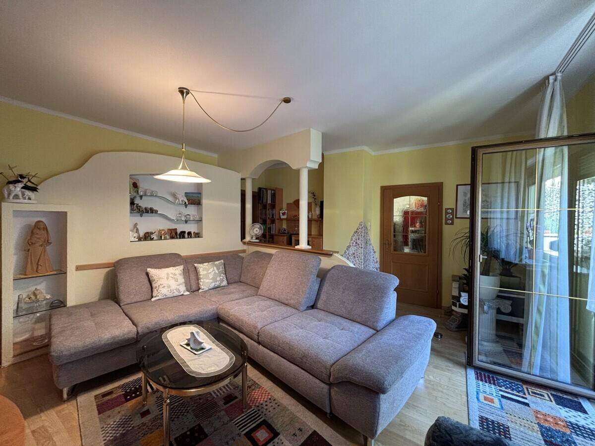 Geräumiges Wohnzimmer mit großem Ecksofa, dekorativen Nischen und Zugang zur Terrasse.