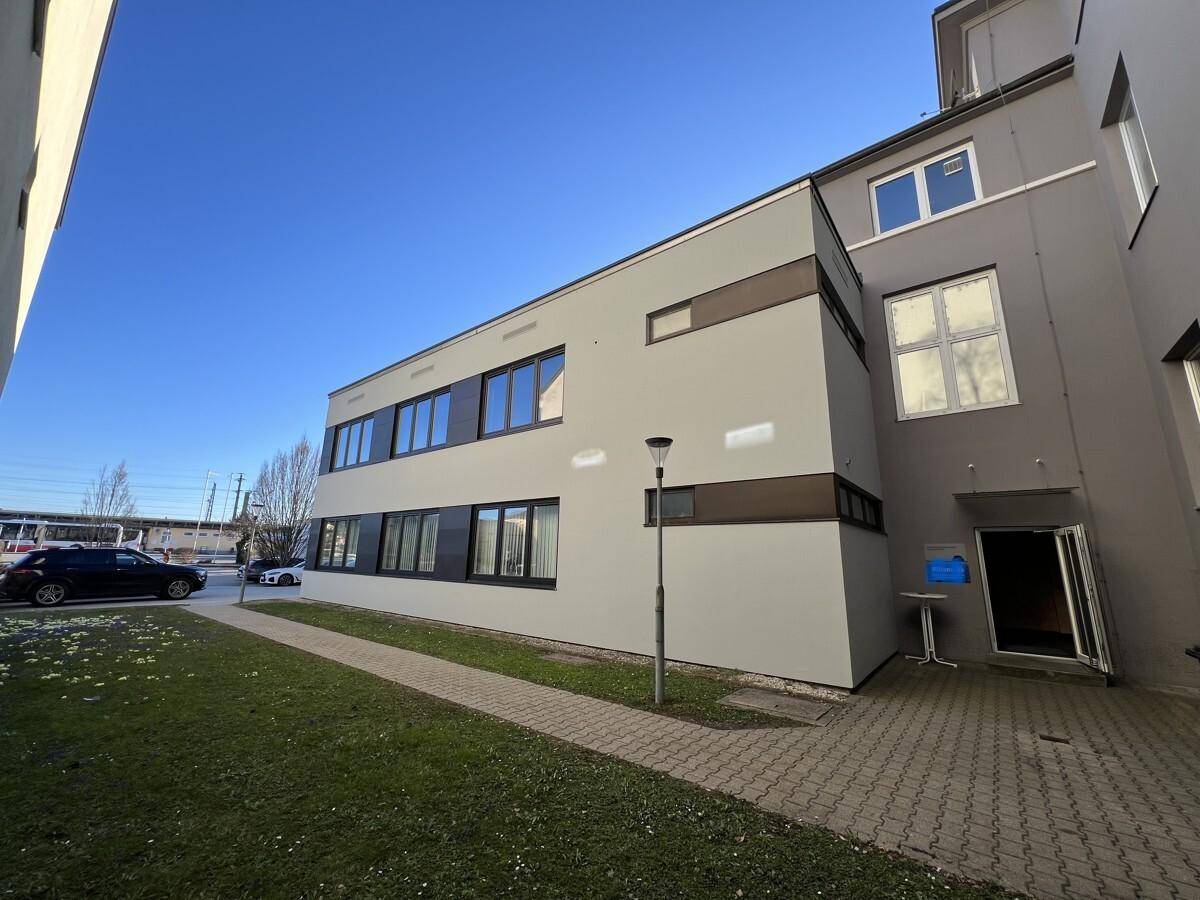 Außenansicht des modernen Bürogebäudes mit Grünfläche und Parkmöglichkeiten.