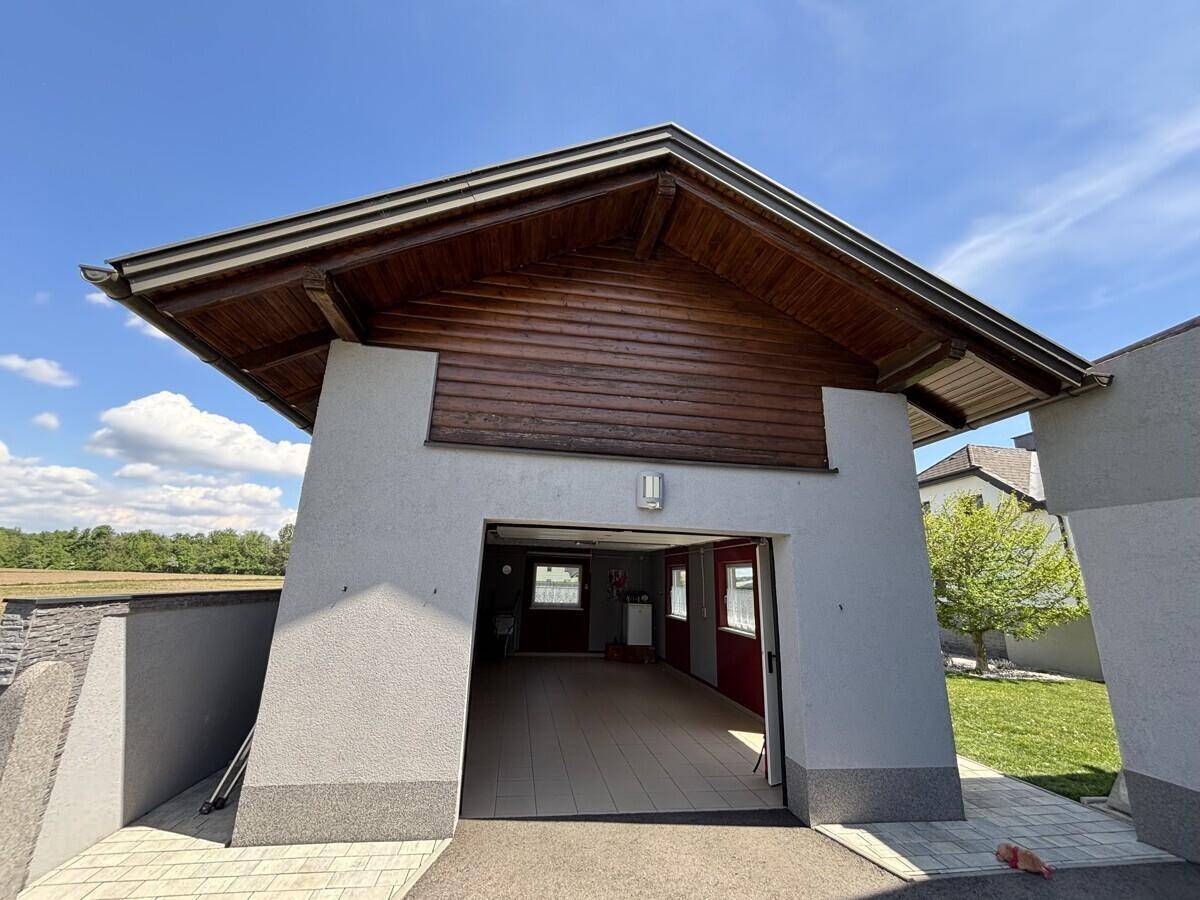 Außenansicht der Garage mit Holzelementen und Zufahrt zum Grundstück.
