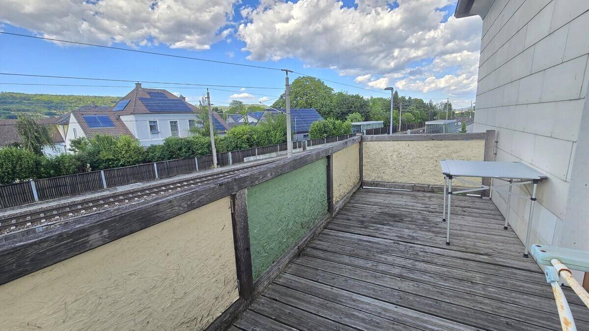 Balkon mit Holzboden und weitem Blick über Bahngleise, Häuser und die ländliche Landschaft.