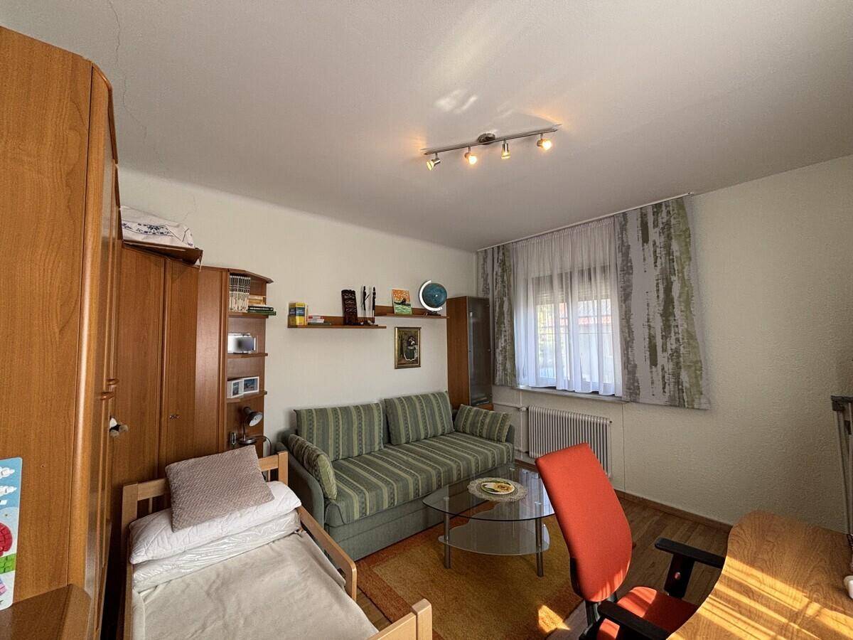 Helles Schlafzimmer oder Gästezimmer mit Einzelbett, Sofa und Schreibtisch.