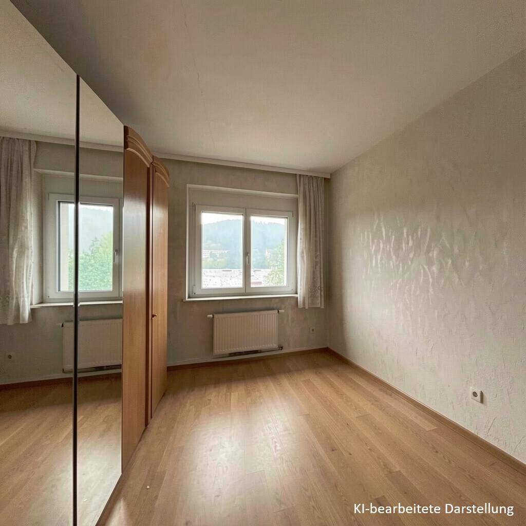 Schlafzimmer mit Parkettboden, Spiegelschrank und Fenster mit Blick auf die bewaldete Umgebung.