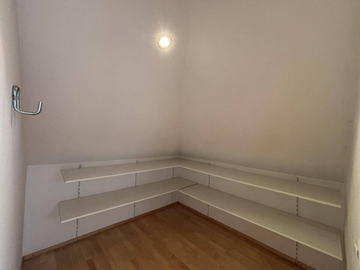 Praktischer Abstellraum im Dachgeschoss mit Regalen und Holzboden für zusätzlichen Stauraum.