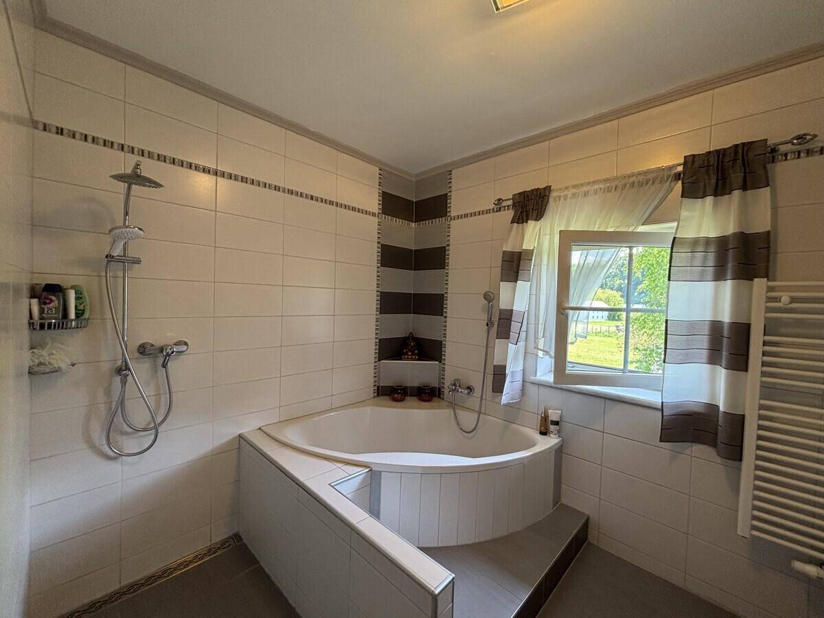 Badezimmer mit Eckbadewanne, Duschfunktion und Fliesen in Braun- und Beigetönen.