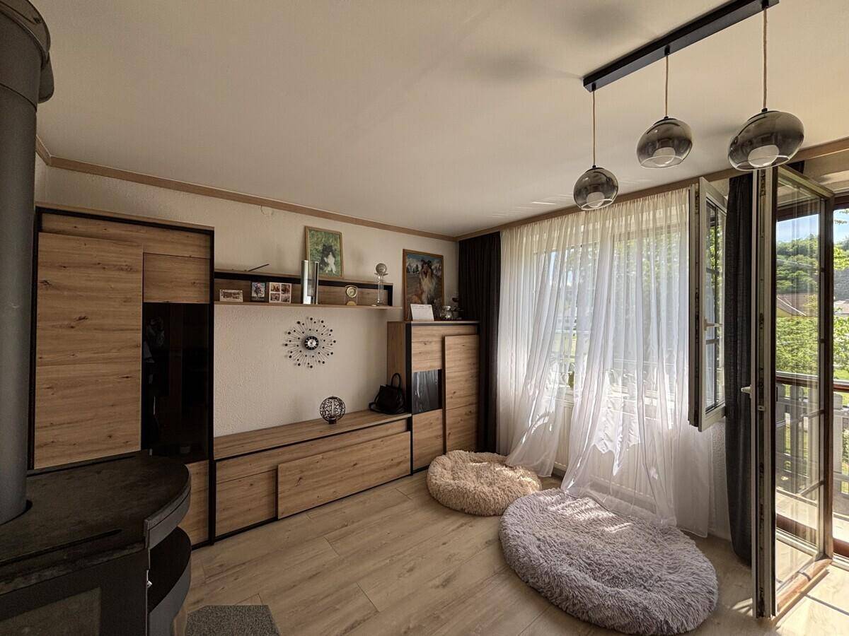 Wohnzimmer mit Holzboden, modernem Wandregal und einem Holzofen für zusätzliche Wärme.