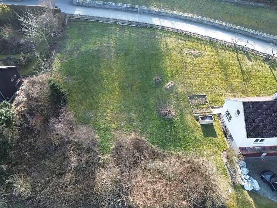 Überblick über ein grünes Grundstück mit angrenzendem Wohnhaus und umliegender Bebauung.