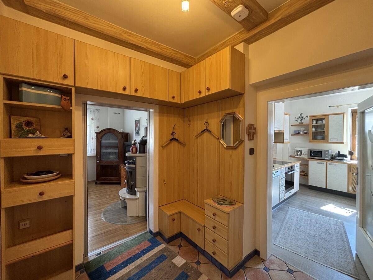 Eingangsbereich mit Holzmöbeln, Garderobe und Blick in angrenzende Räume.