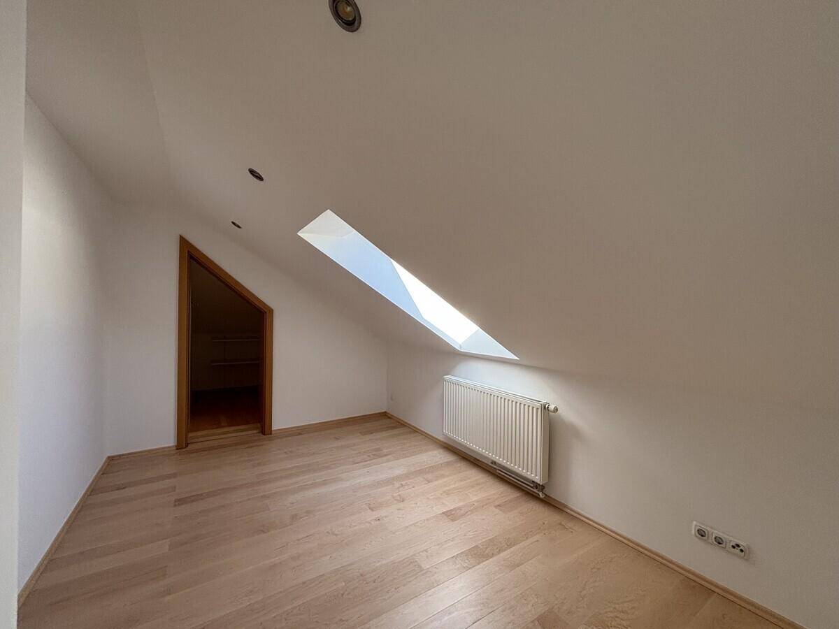 Gemütliches Zimmer im Dachgeschoss mit Holzboden, Dachfenster und Heizkörper, ideal als Schlaf- oder Arbeitszimmer.