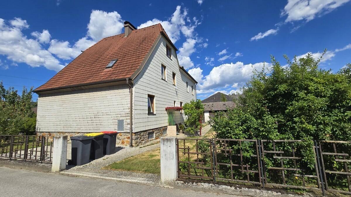 Seitenansicht des Hauses von der Straße aus mit Garten und blauen Himmel.