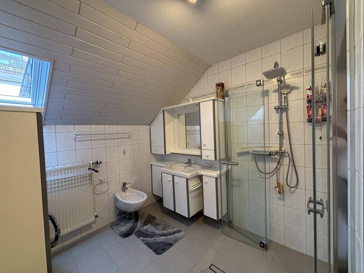 Modernes Badezimmer mit Dachschräge, Dusche, Bidet und Doppelwaschbecken.