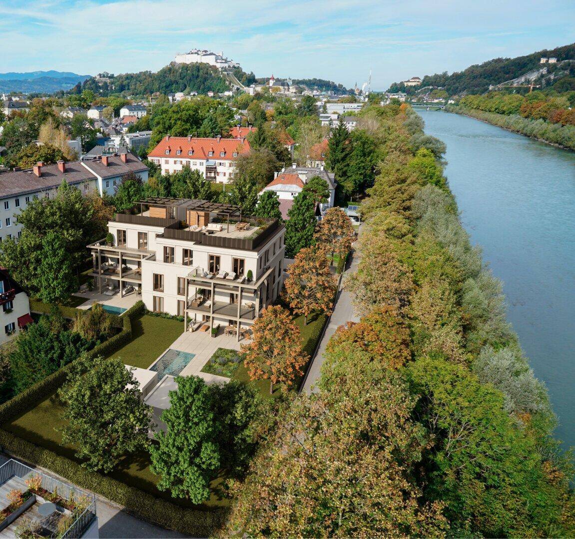 Luftaufnahme der modernen Wohnanlage am Flussufer mit Blick auf die Stadt und Berge.