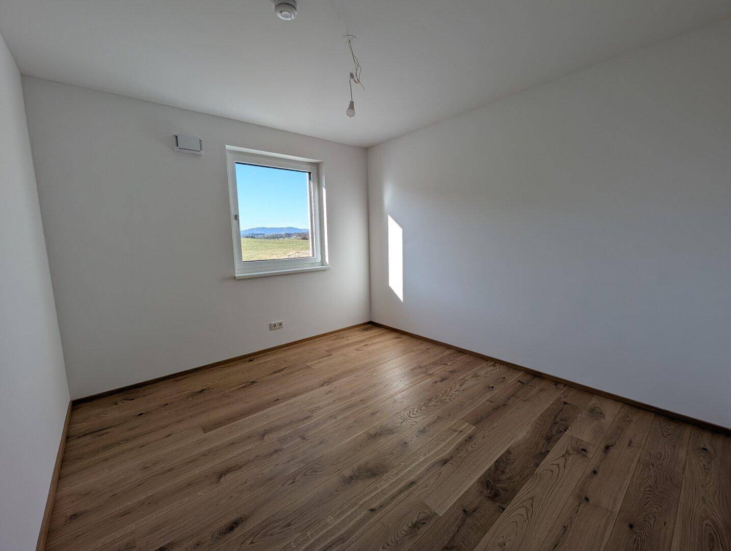 Sonniger Raum mit Eichenparkett und weiß gestrichenen Wänden, ideal als Schlafzimmer oder Arbeitszimmer.