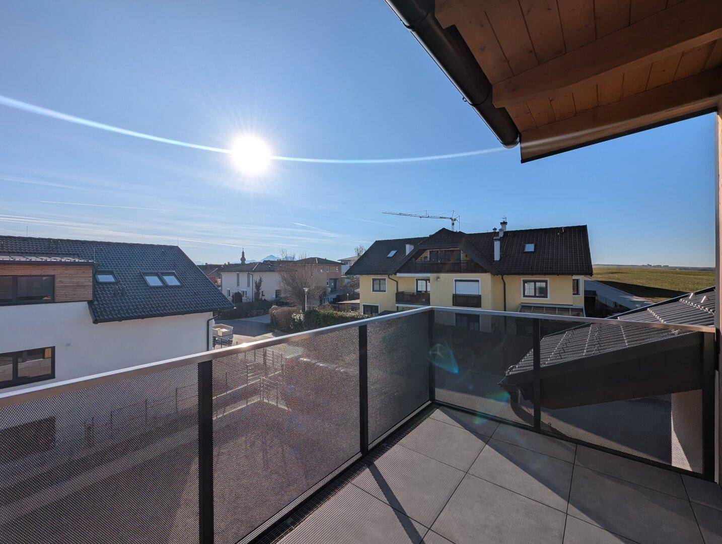 Sonniger Balkon mit Blick auf die Nachbarschaft und die umliegende Landschaft.