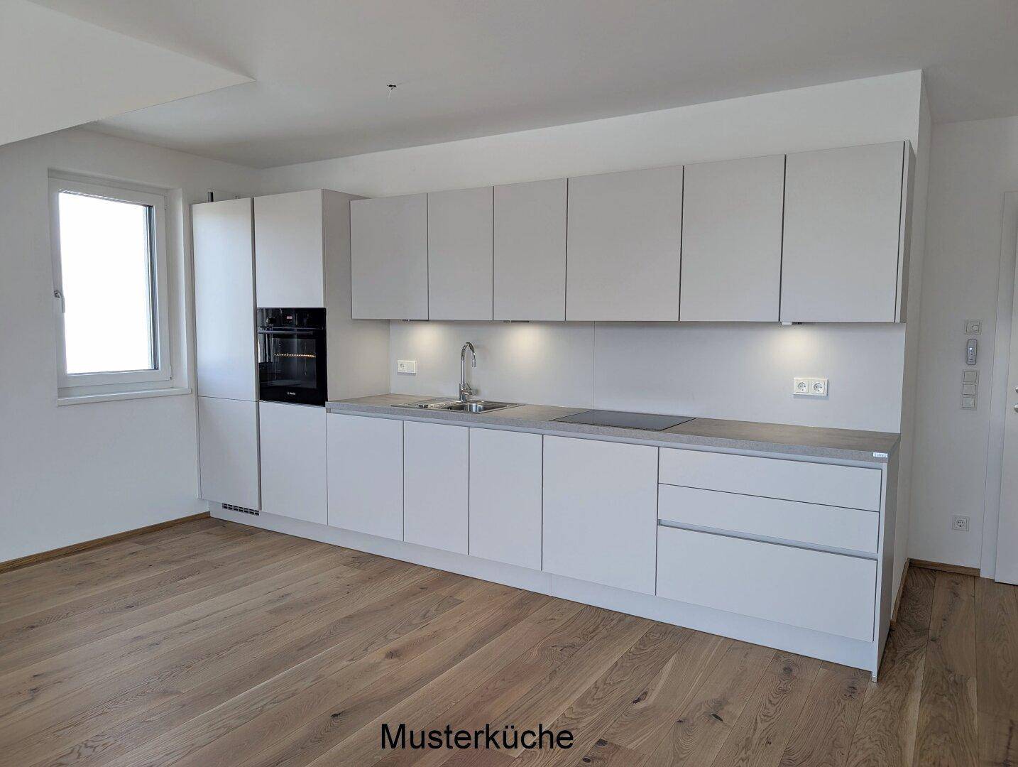 Moderne Einbauküche in hellem Grau mit integrierten Geräten und Holzboden in einem Neubau.