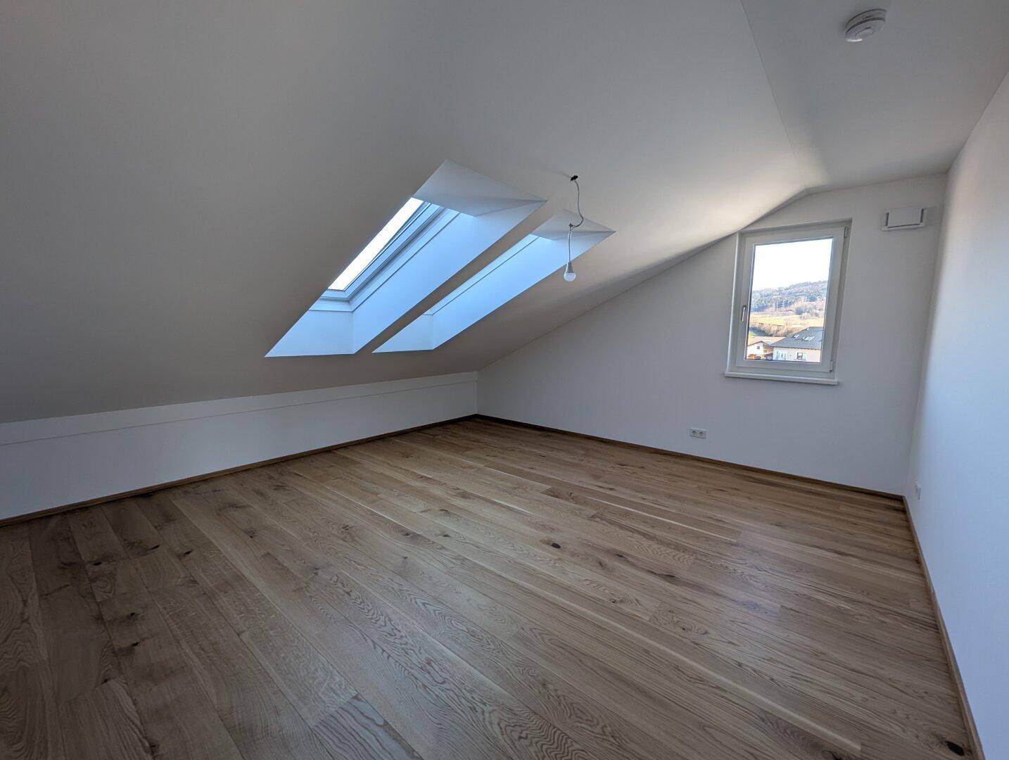 Geräumiges Schlafzimmer im Dachgeschoss mit Eichenparkett und großem Dachfenster für viel Helligkeit.