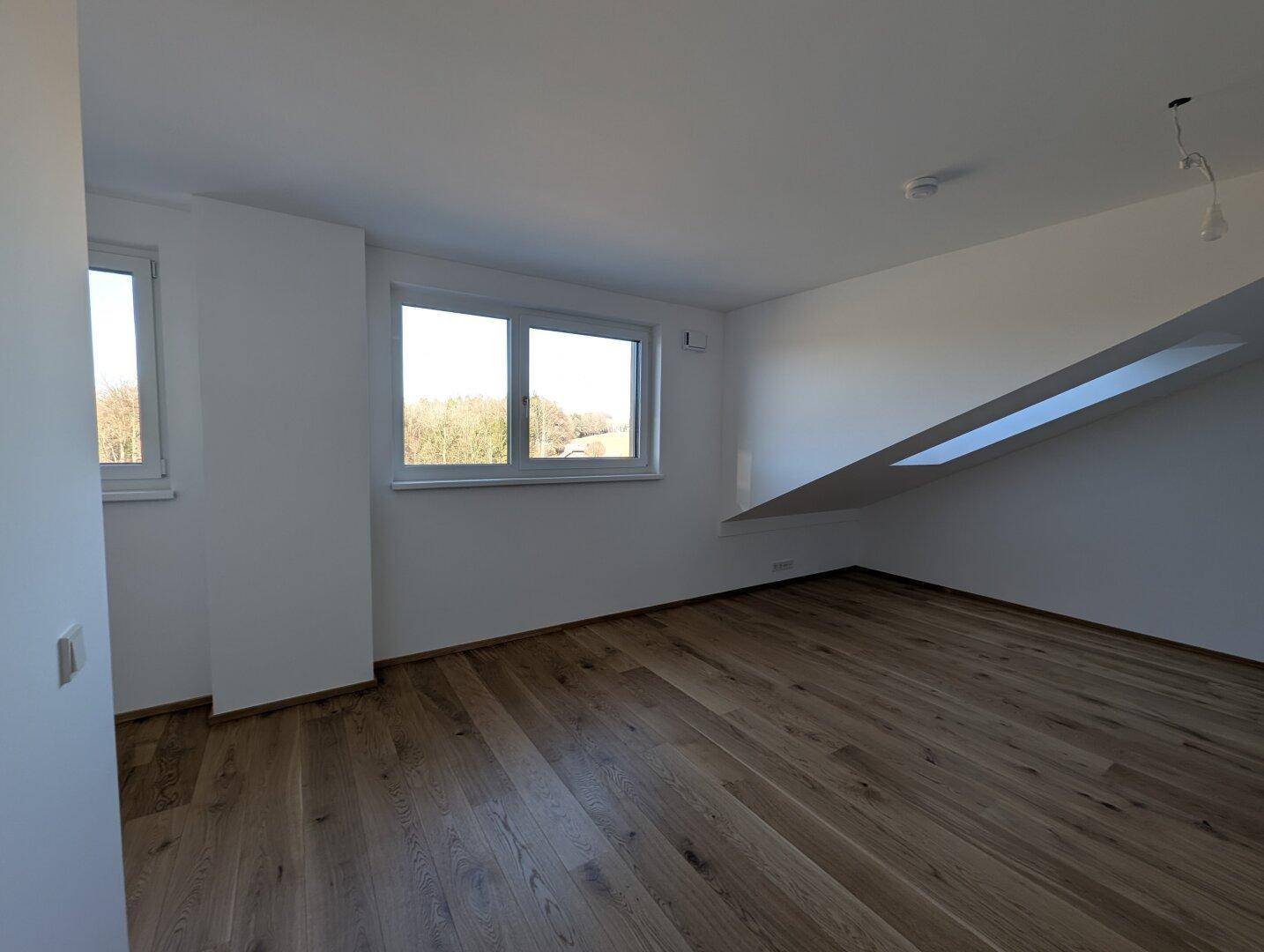 Lichtdurchflutetes Schlafzimmer mit Eichenparkett, Fenster und Dachfenster, bietet eine angenehme Atmosphäre.
