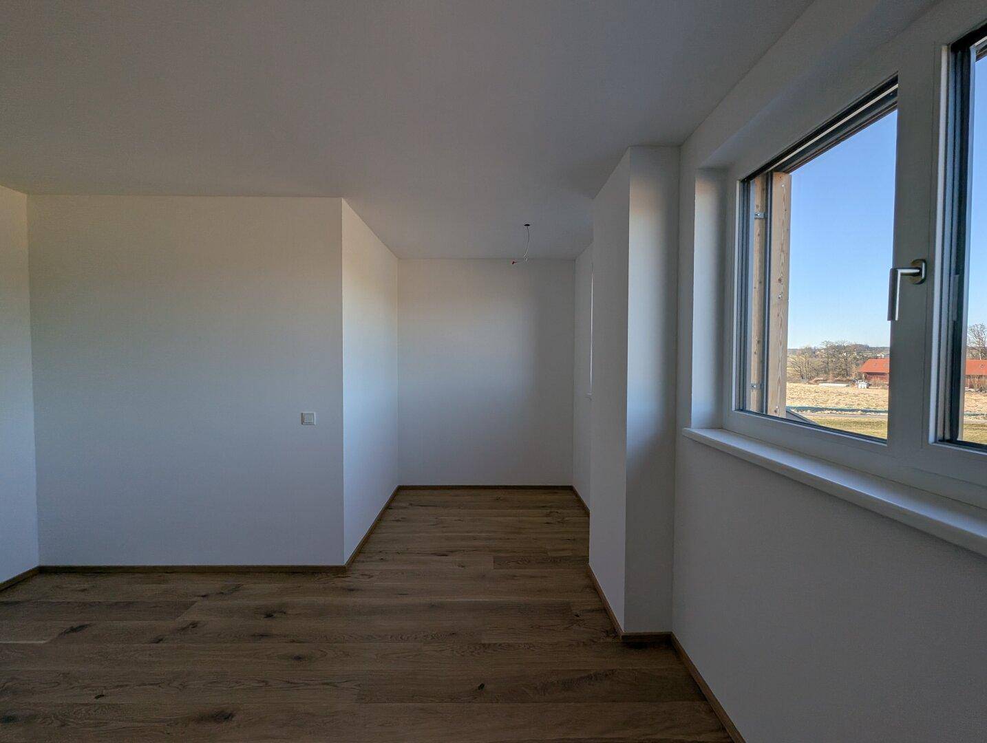 Heller Flur mit Eichenparkett und großem Fenster, das viel Tageslicht in den Raum bringt.