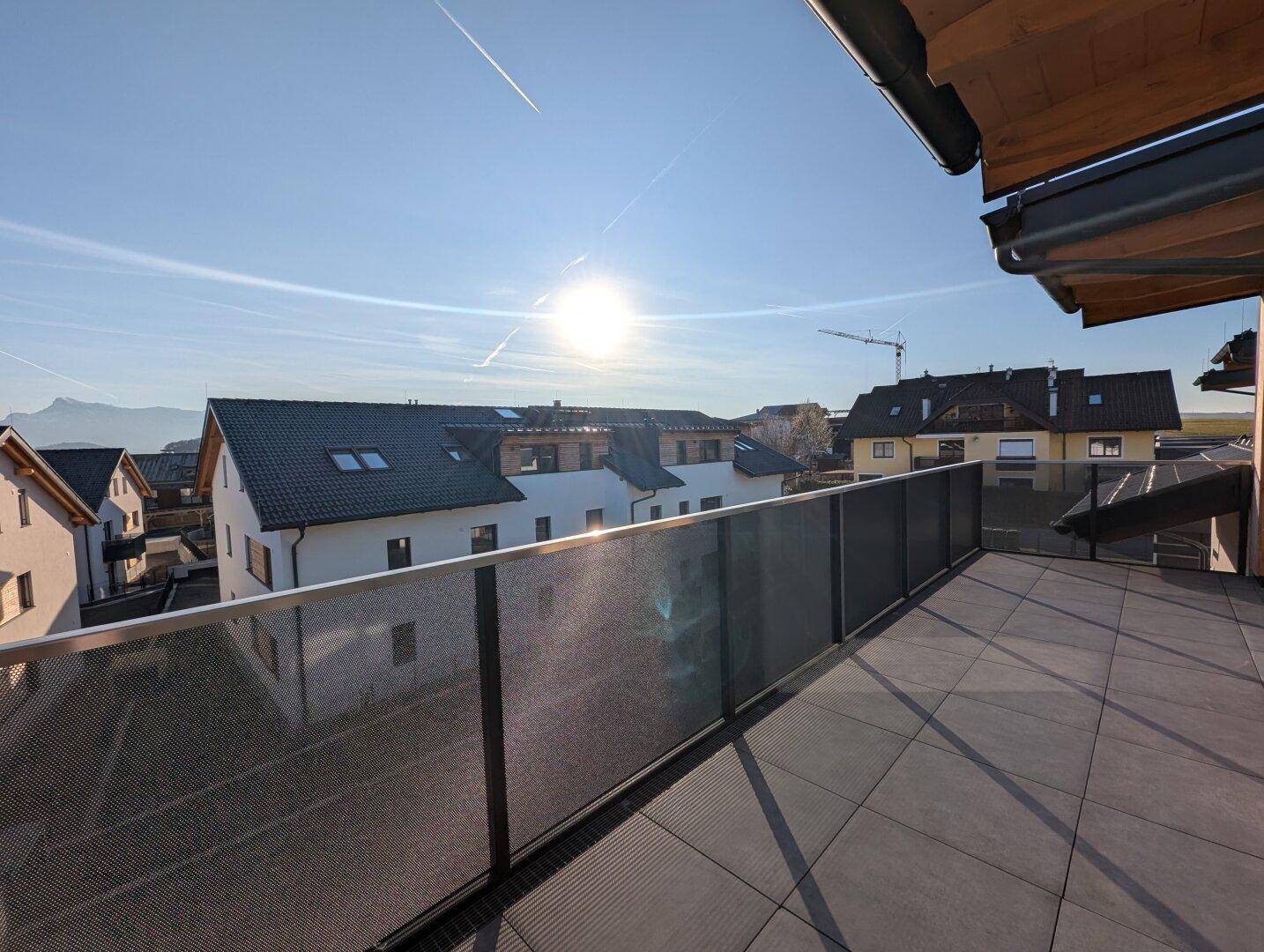 Sonniger Balkon mit Fliesenboden und modernem Geländer, bietet einen weiten Blick auf die Umgebung.