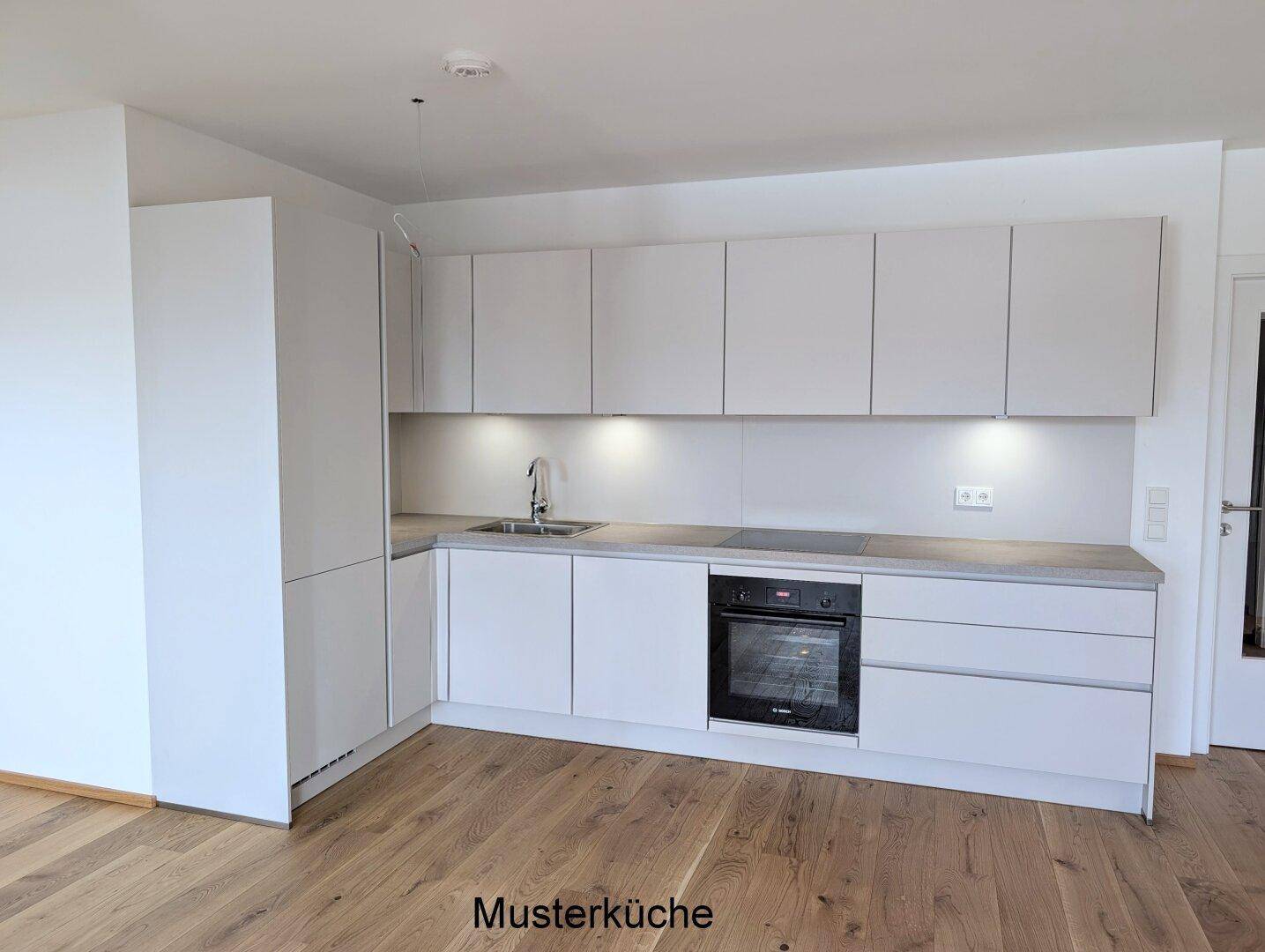 Moderne Einbauküche in hellem Grau mit integrierten Geräten und Holzboden, als Musterküche präsentiert.