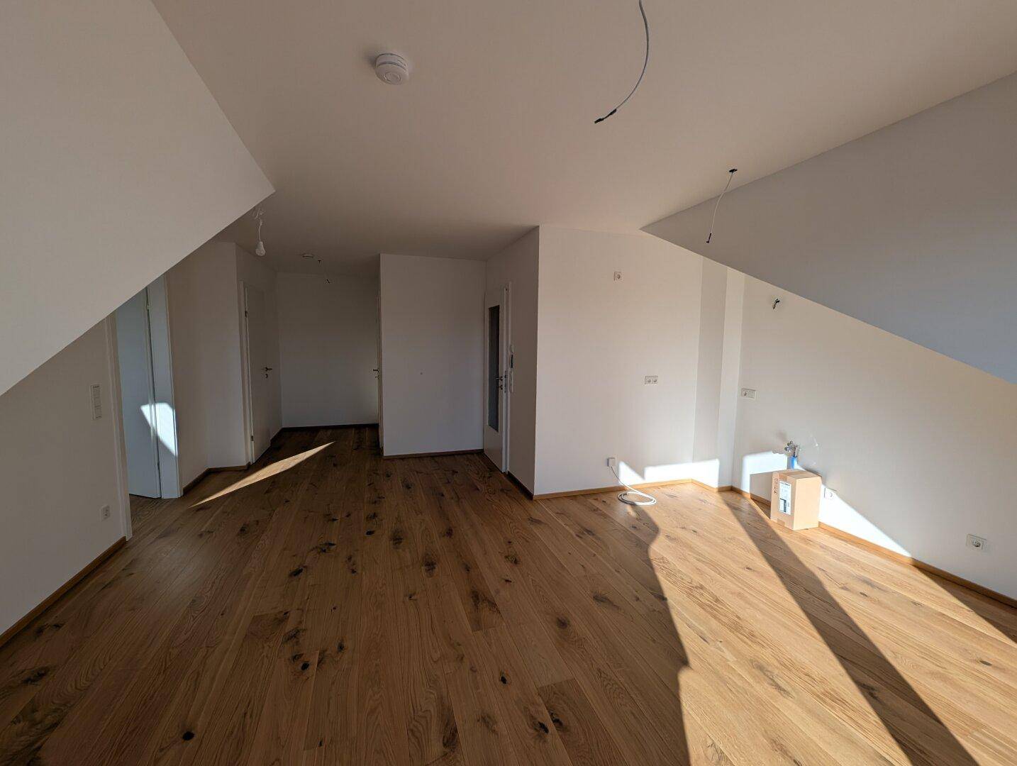 Heller Raum mit Holzboden und Dachschrägen, der vielseitig genutzt werden kann.