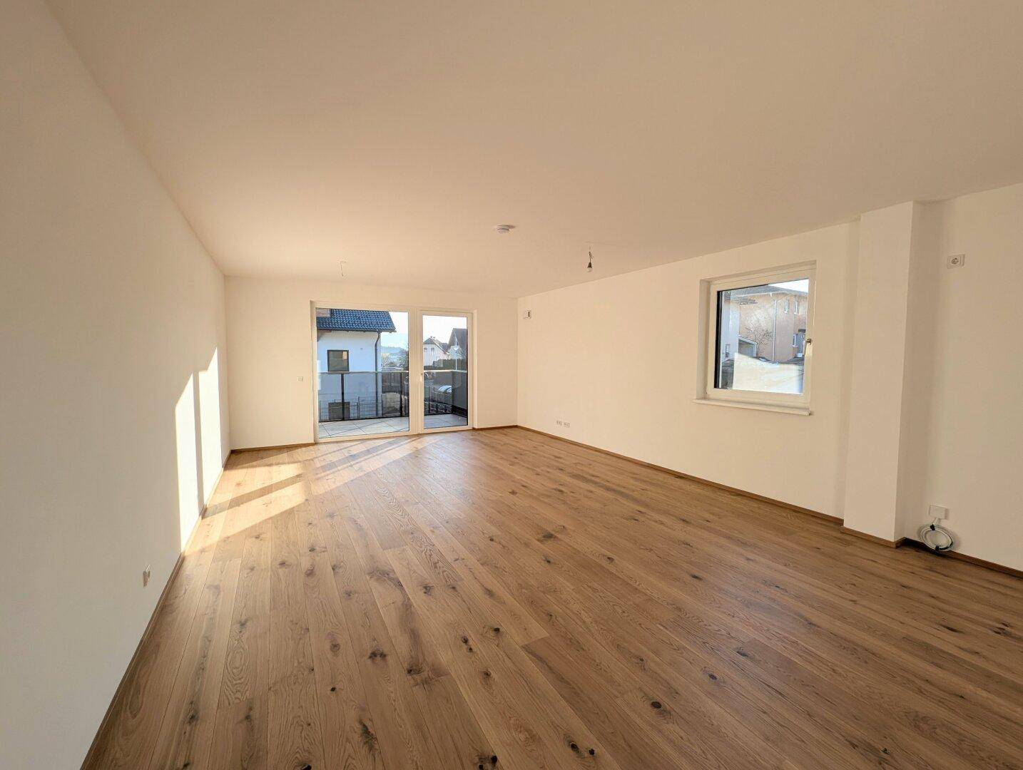 Geräumiges, helles Wohnzimmer mit neuem Eichenparkett und Zugang zu einem Balkon, ideal für offene Gestaltung.