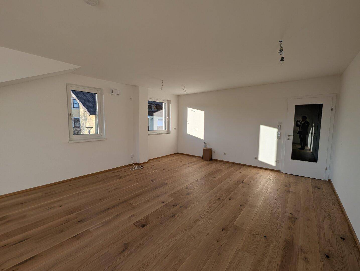 Helles Zimmer mit Holzboden und großen Fenstern, ideal als Schlaf- oder Arbeitszimmer.