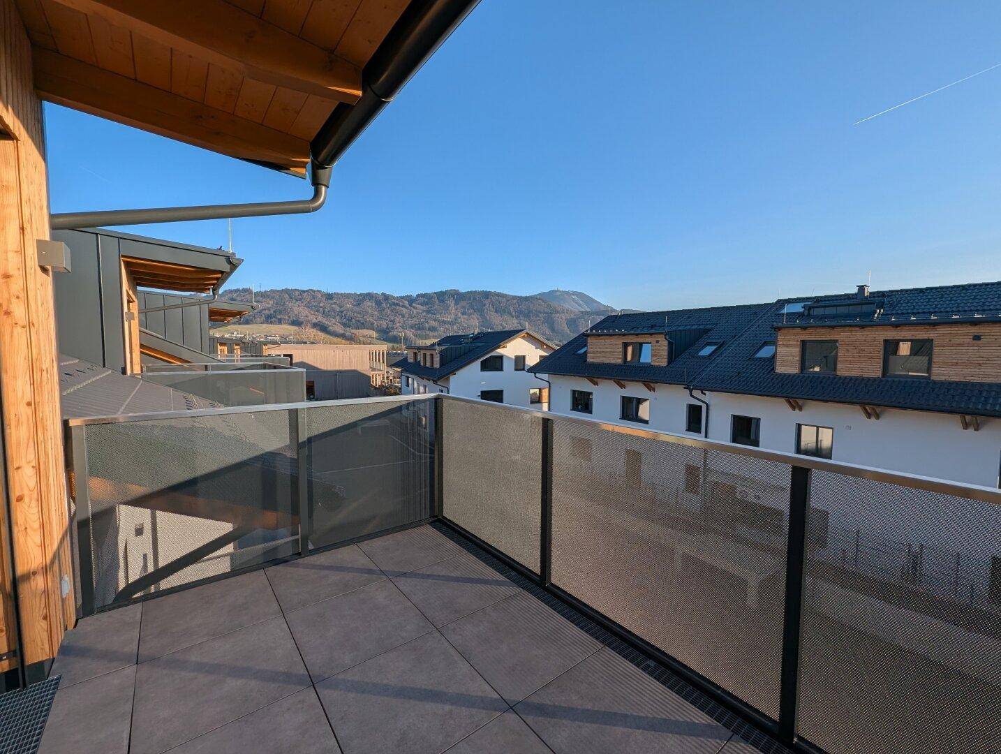 Geräumiger Balkon mit Glasgeländer und weitem Blick auf die umliegende Berglandschaft.