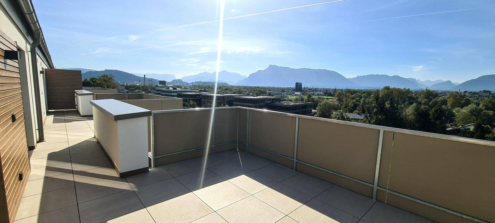 Geräumige Sonnenterrasse mit Fliesenboden und weitem Blick auf die Berge und die Stadt.