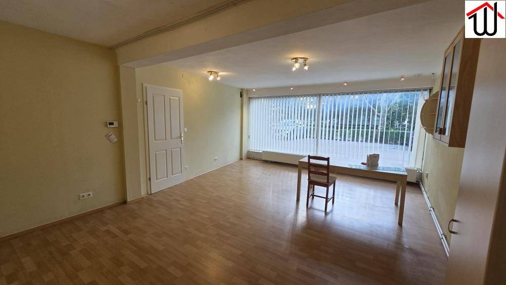 Heller Mehrzweckraum mit großen Fenstern, die viel Tageslicht hereinlassen, und Laminatboden.