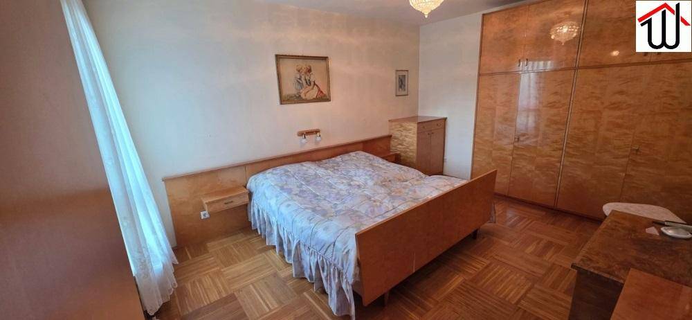 Schlafzimmer mit Doppelbett, großem Holzschrank und Parkettboden, bietet eine ruhige Atmosphäre.