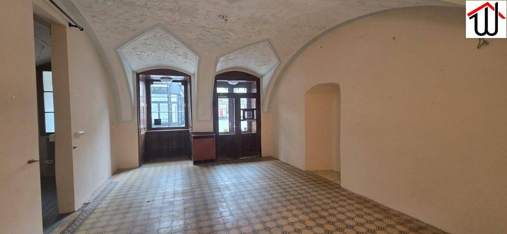 Geräumiger Raum mit Gewölbedecken, gemusterten Fliesen und zwei großen Fenstern, die viel Licht spenden.