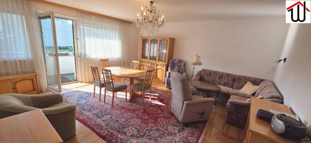 Geräumiger Wohn-Essbereich mit Esstisch, Sofa und Zugang zum Balkon, hell und einladend gestaltet.
