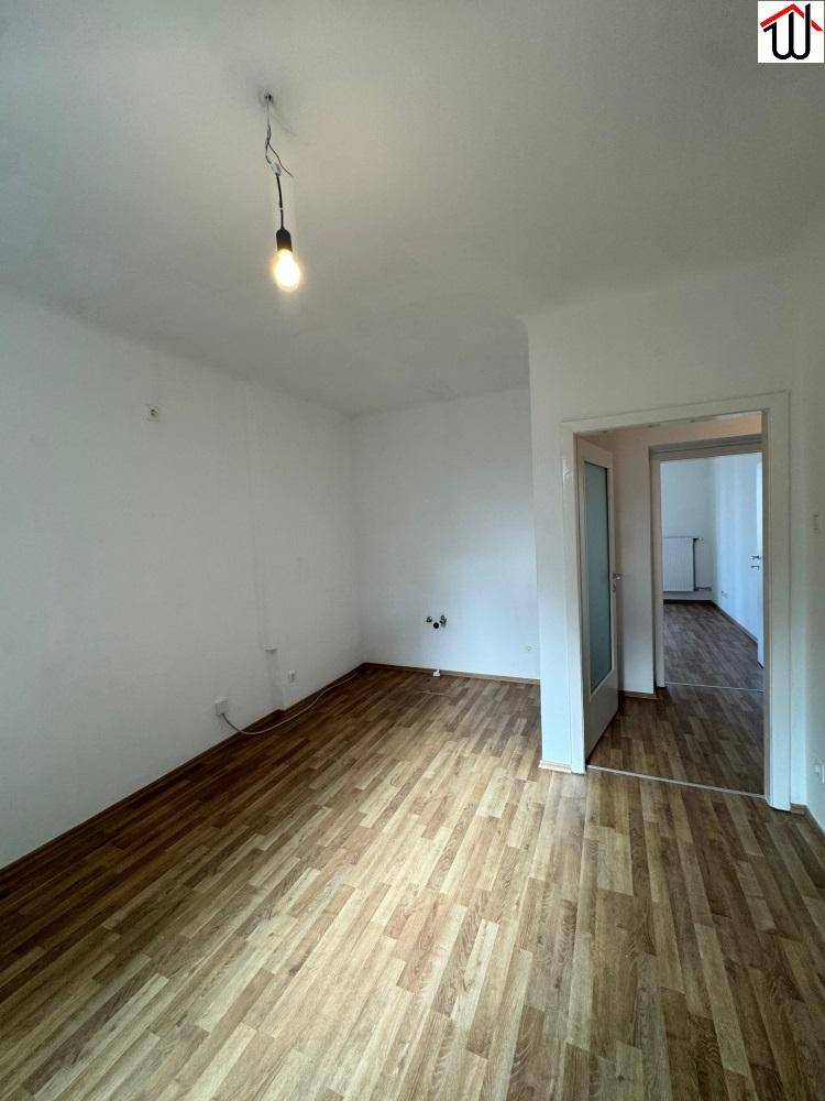 Leerer Raum mit Laminatboden und Anschlüssen an der Wand, vielseitig nutzbar.