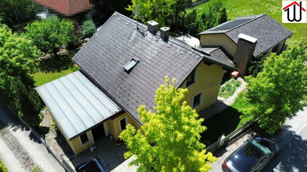 Luftaufnahme des Hauses mit Satteldach, Carport und umliegender grüner Landschaft.