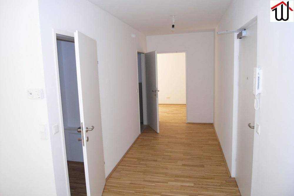 Heller Flur mit Holzboden und mehreren Türen, der zu verschiedenen Räumen führt.