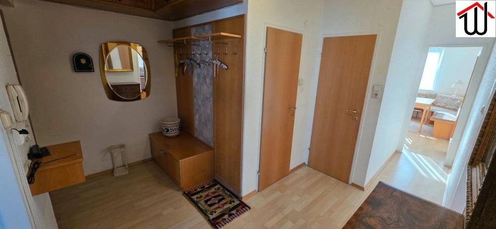 Heller Flur mit Garderobe, Spiegel und Holzmöbeln, bietet praktischen Stauraum im Eingangsbereich.