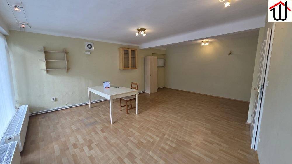 Vielseitiger Raum mit Laminatboden, Heizkörpern und einem kleinen Tisch mit Stuhl.