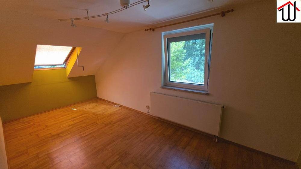 Geräumiges Schlafzimmer im Dachgeschoss mit Holzboden und zwei Fenstern.