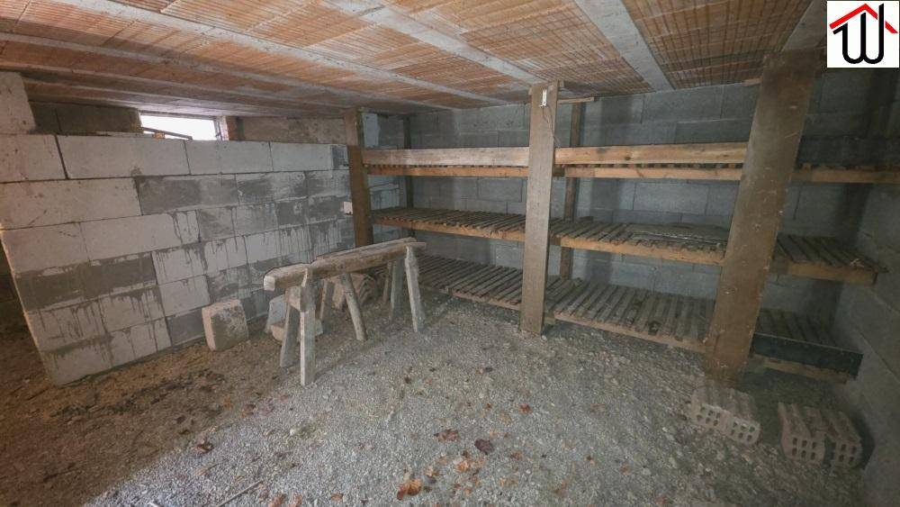 Kellerraum mit Betonsteinwänden, Holzregalen und unfertigem Boden, ideal als Lager.
