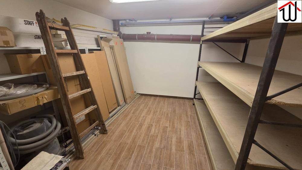 Funktionaler Abstellraum im Keller mit Regalen, einer Leiter und Fliesenboden für Lagerzwecke.