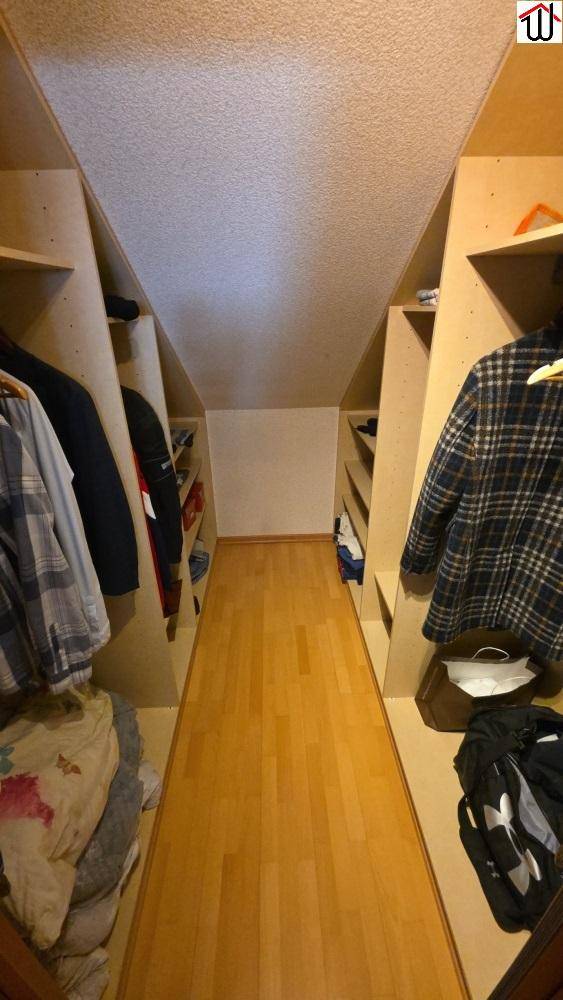 Begehbarer Kleiderschrank im Dachgeschoss mit maßgefertigten Regalen und Holzboden.