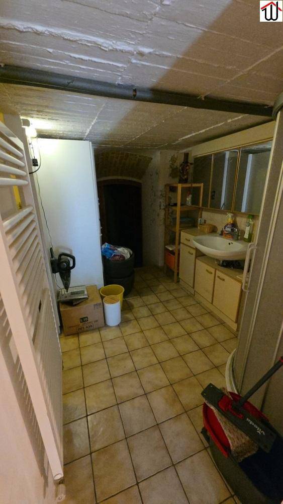 Kellerraum mit Waschbecken, Stauraum und gefliestem Boden, vielseitig nutzbar.