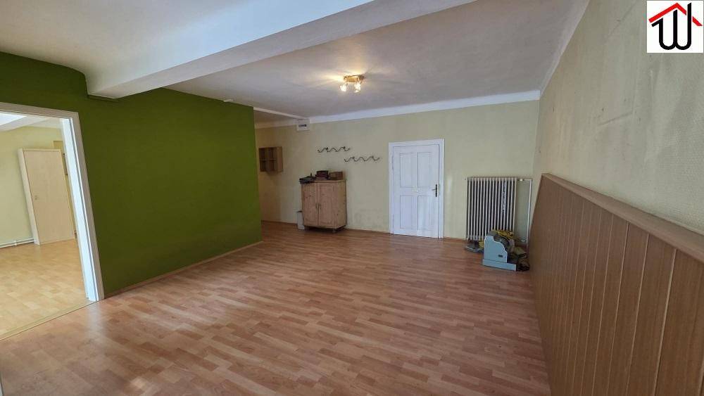 Großer, heller Mehrzweckraum mit Laminatboden und einer grünen Akzentwand.