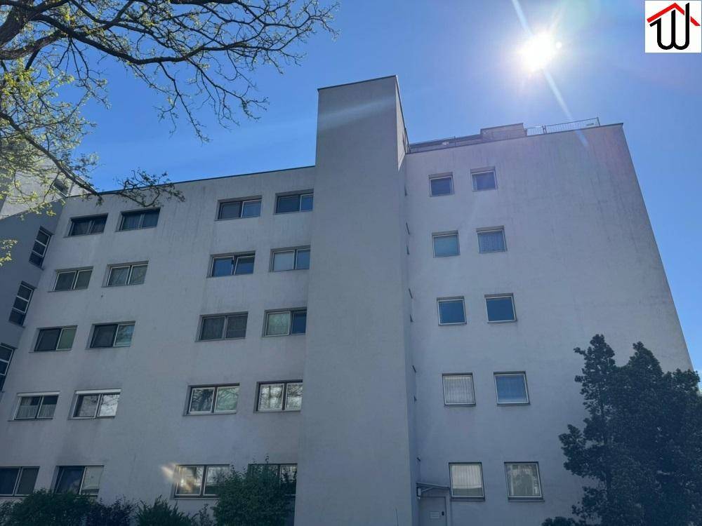 Mehrstöckiges Wohngebäude mit vielen Fenstern unter strahlend blauem Himmel, moderne Architektur.