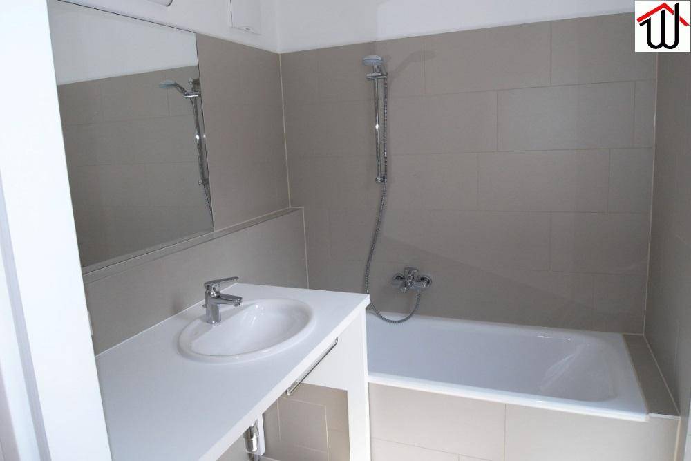 Badezimmer mit Badewanne, Einzelwaschbecken und modernen grauen Fliesen.