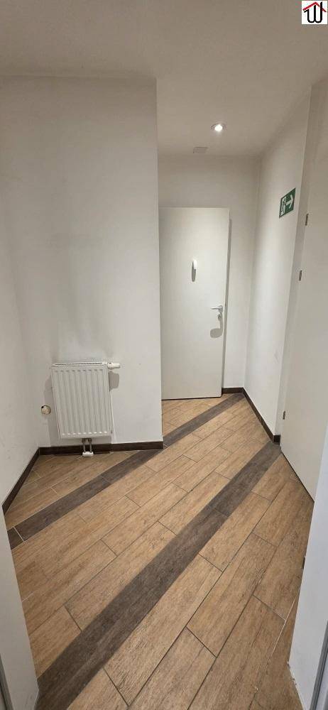 Heller Flur mit Holzboden, weiß gestrichenen Wänden und einem Heizkörper.