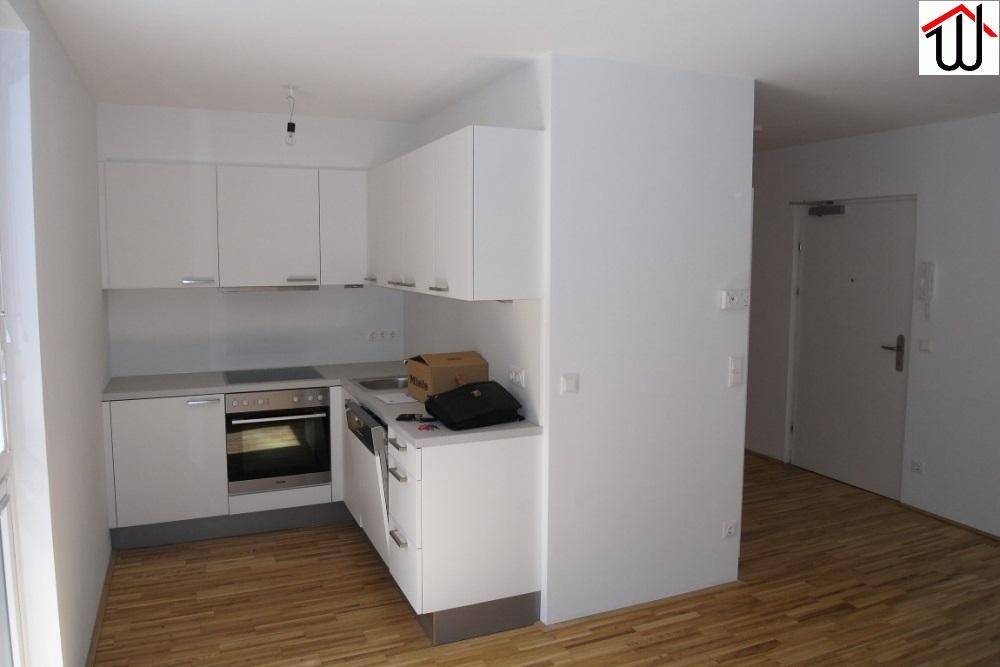 Moderne Küchenzeile mit weißen Schränken, integriertem Backofen und Spülmaschine.
