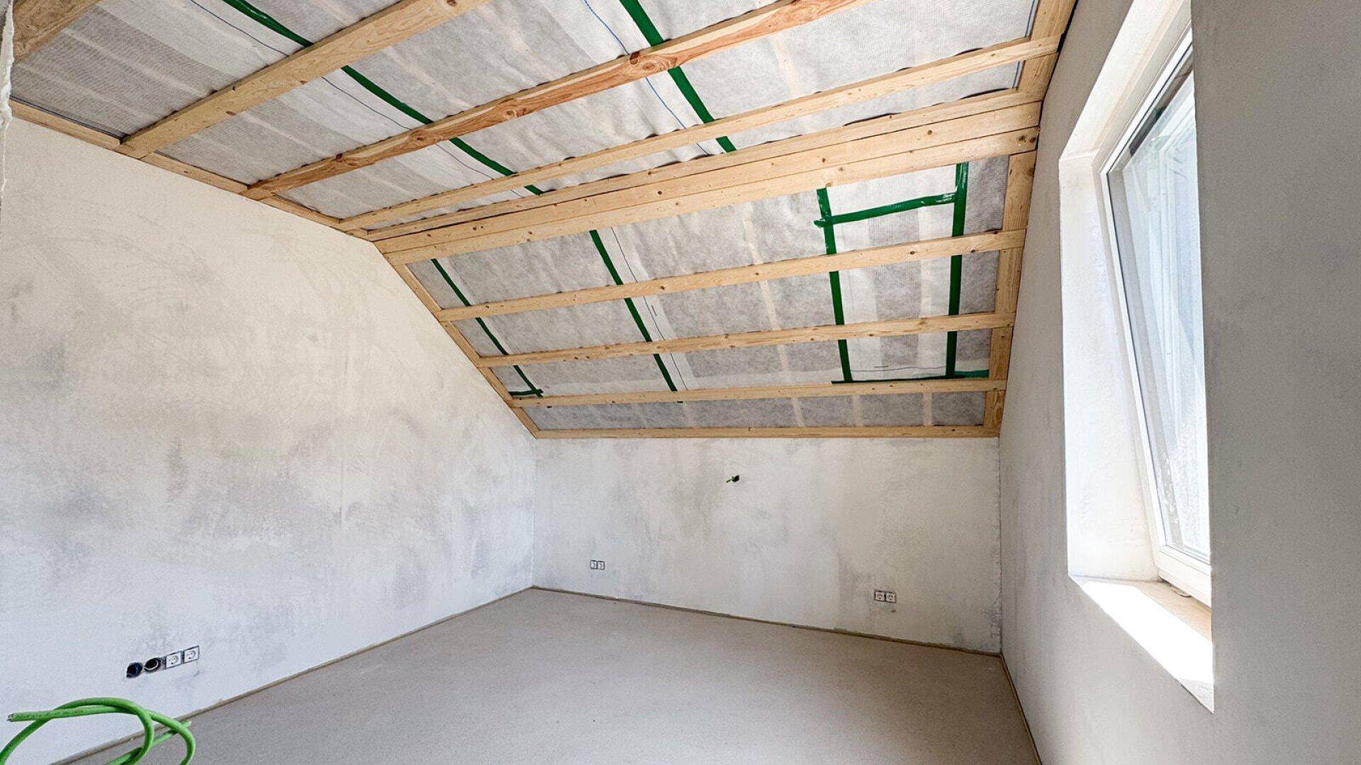 Unfertiger Dachraum mit sichtbarer Holzkonstruktion und schrägen Wänden, ideal für individuellen Ausbau.