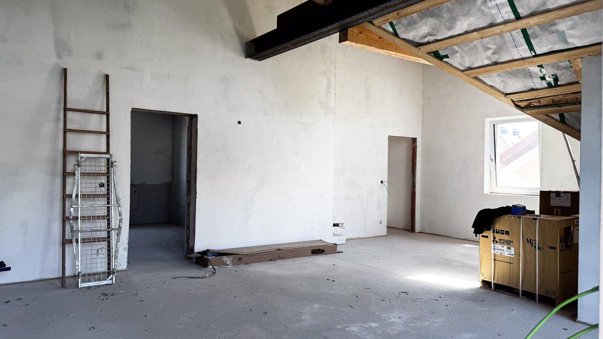 Großer, unfertiger Raum mit hohen Decken und sichtbaren Dachbalken, bietet viel Gestaltungspotenzial.