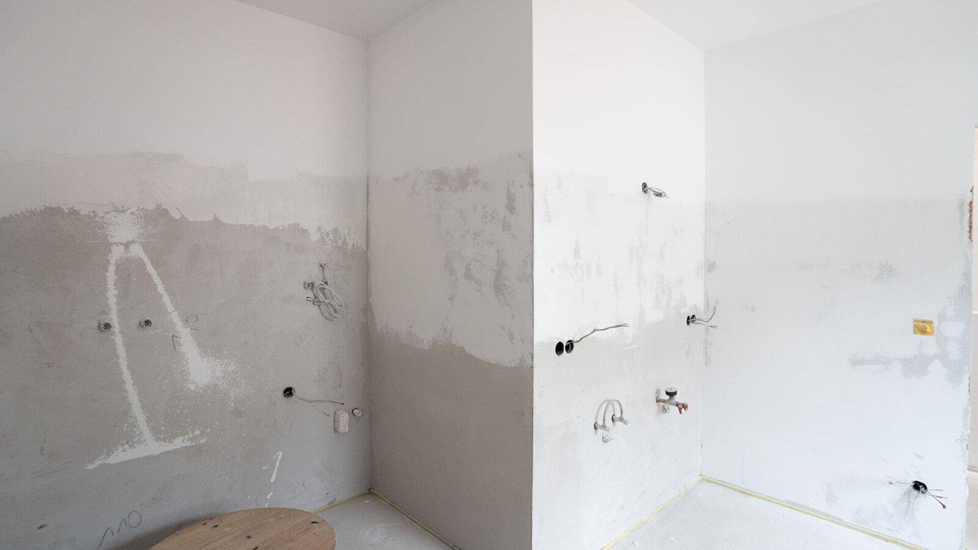 Badezimmer im Rohbau mit sichtbaren Wasseranschlüssen und unfertigen Wänden.